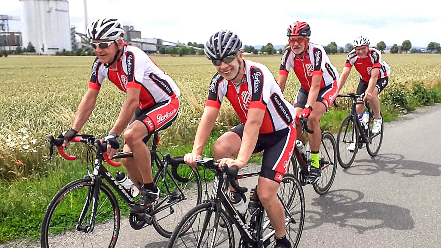 Team Parlasca Keks fährt mit vier Personen auf einer Landstraße mit Fahrrädern entlang