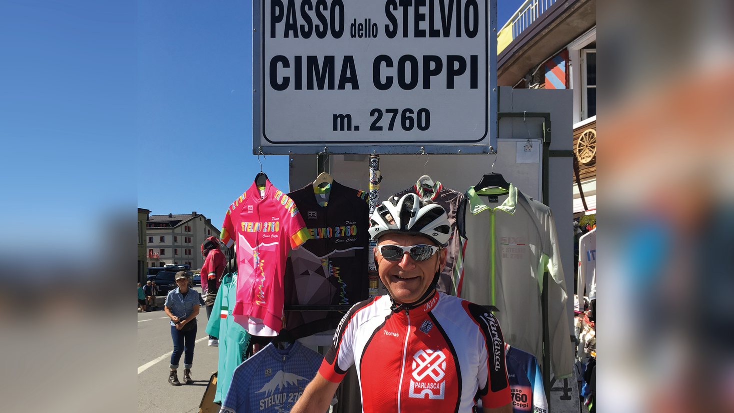 Fahrradfahrer des Team Parlasca Keks in Italien vor einem Shop mit bunten Fahrradtrikots
