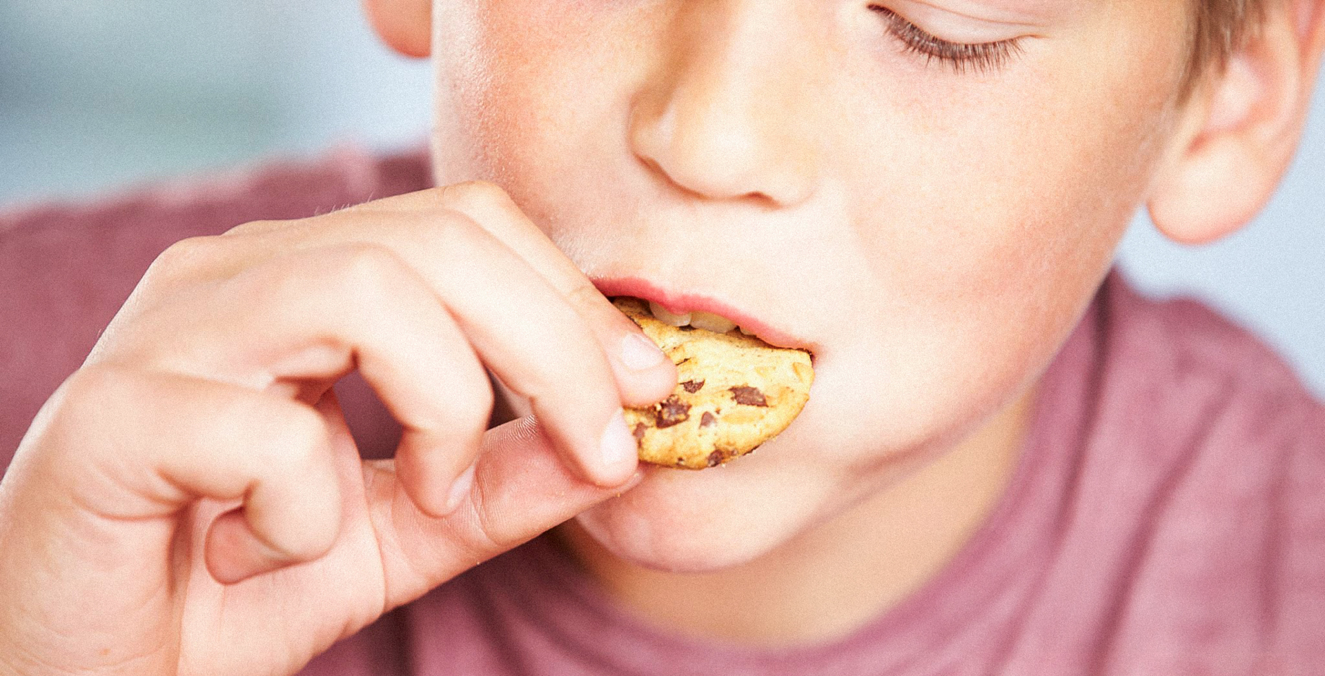 Kind beißt in Keks mit Schokostücken