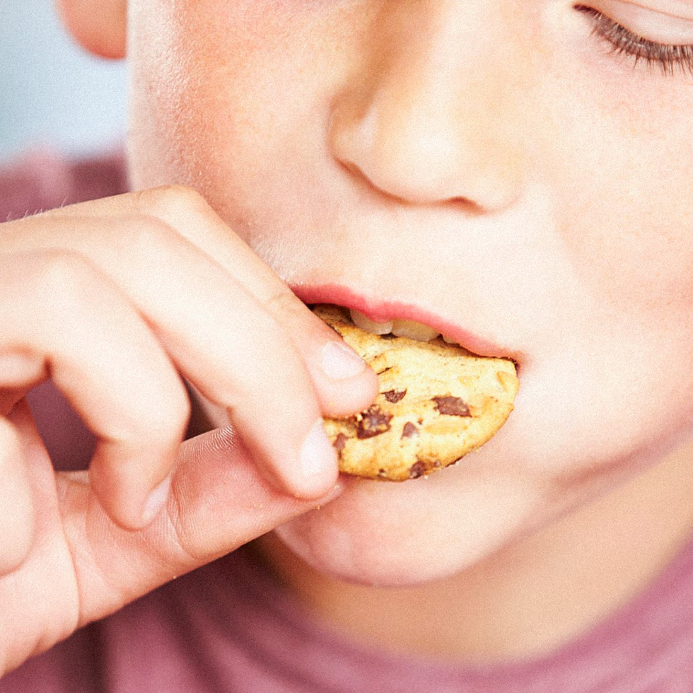 Kind beißt in Keks mit Schokostücken