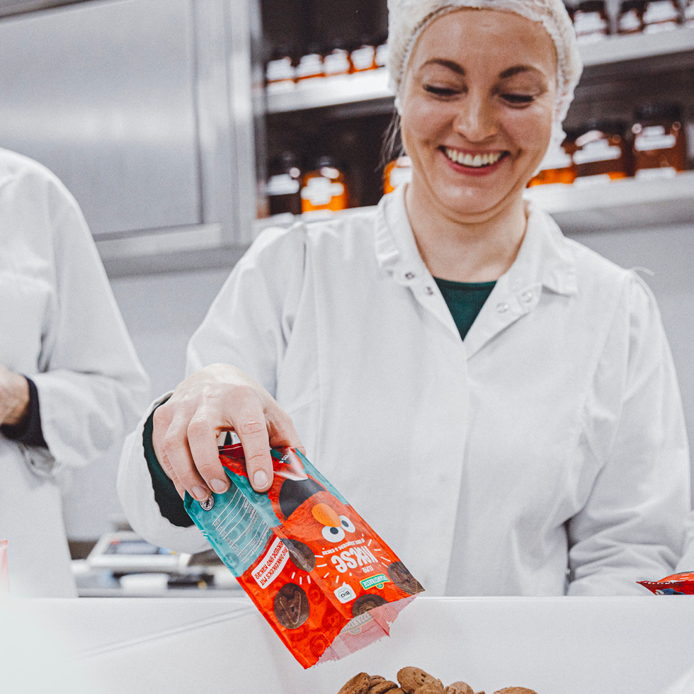 Mitarbeiterin schüttet Kakaokekse aus einer Verpackung mit Sesamstrasse Elmo Motiv in eine Schale