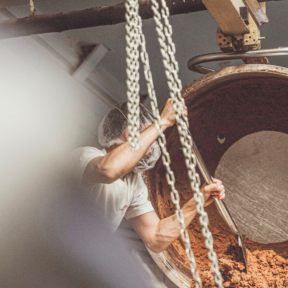 Ein Mitarbeiter entnimmt mithilfe einer Schaufel den Keksteig aus der Knetmaschine