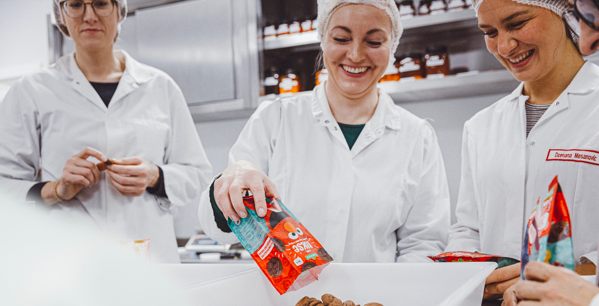 Mitarbeiterinnen schütten Kakaokekse aus einer Verpackung mit Sesamstrasse Elmo Motiv in eine Schale