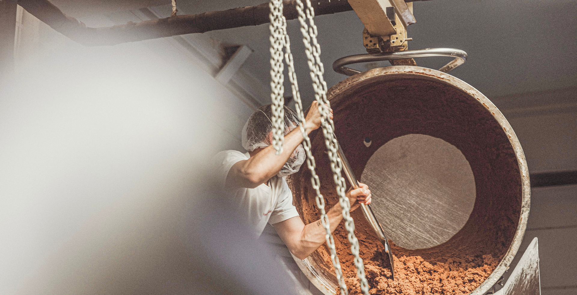 Ein Mitarbeiter entnimmt mithilfe einer Schaufel den Keksteig aus der Knetmaschine