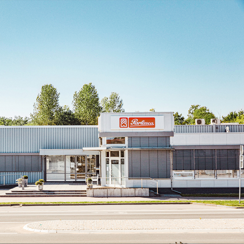 Außenansicht des Gebäudes der Parlasca Keksfabrik in Deutschland bei sonnigem Wetter mit Eingang und Firmenlogo über der Tür